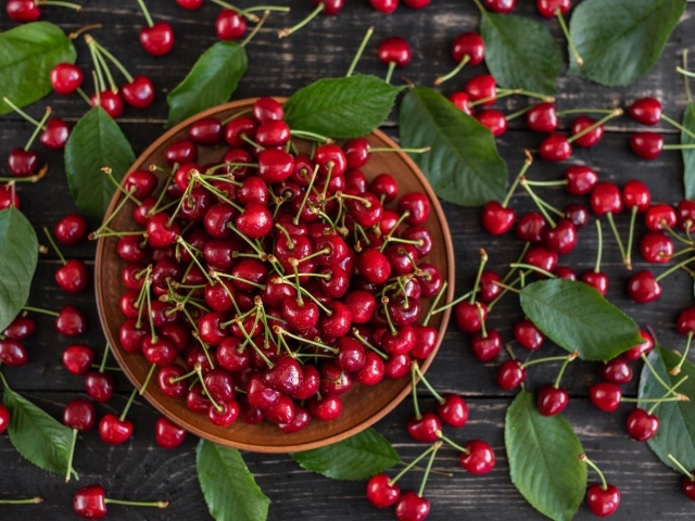 Много спелой красной черешне в миске на столе