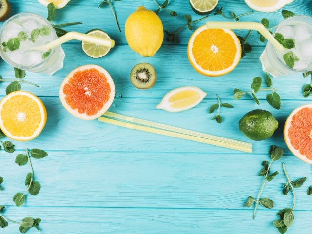 Цитрусовые фрукты на голубом столе с мятой и лимонадом