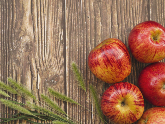 Красные яблоки на деревянном фоне с зелеными колосками