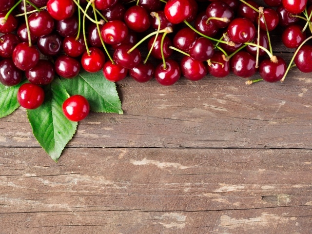 Красные спелые вишни на деревянном столе