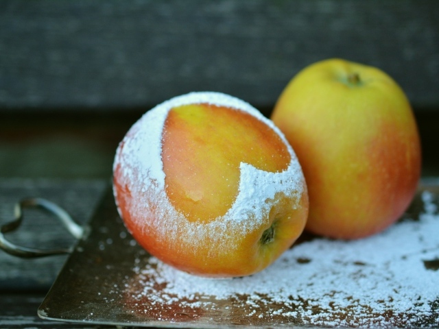 Спелое яблоко с сердцем из сахарной пудры на столе 