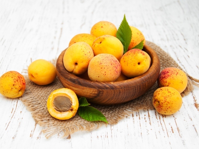 Спелые абрикосы в деревянной миске на столе