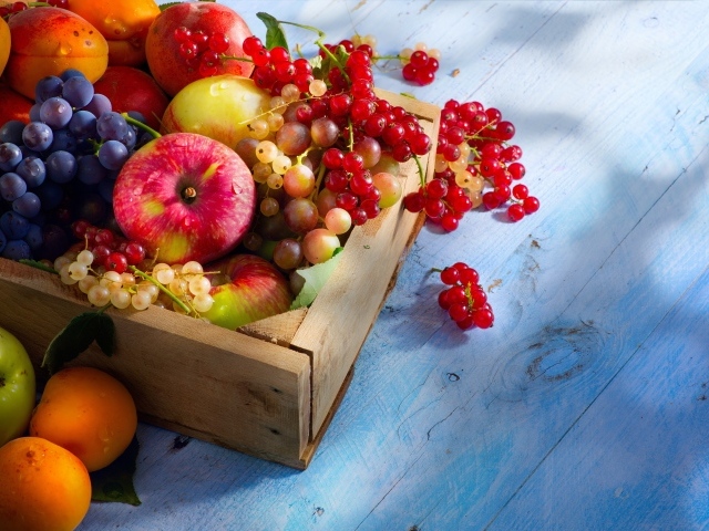 Спелые сочные ягоды и фрукты на столе в деревянном ящике