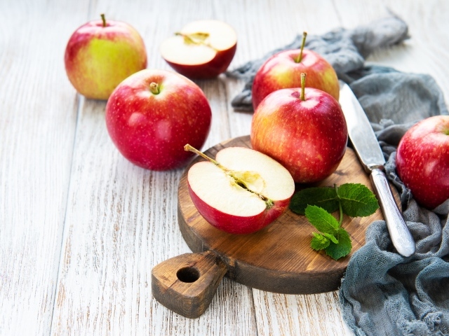 Спелые красные яблоки на разделочной доске с ножом