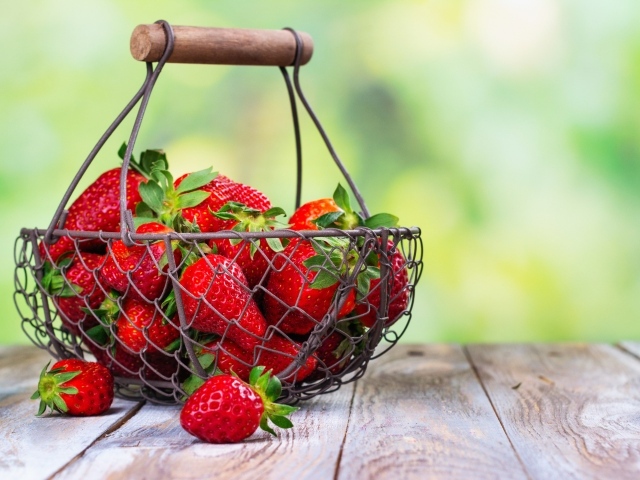 Спелая красная клубника в корзине на столе