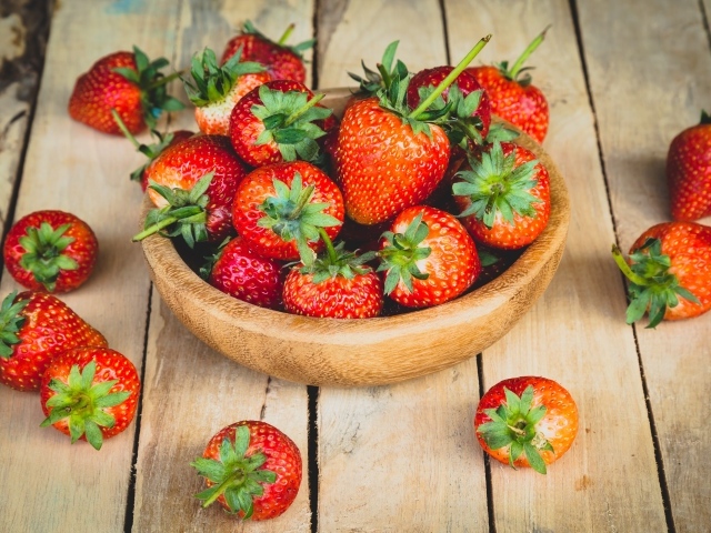 Спелая красная клубника в деревянной миске на столе