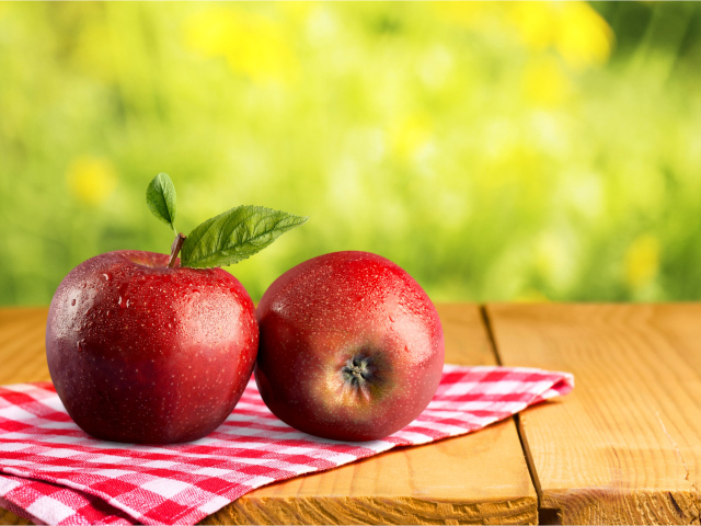 Два красных яблока в каплях воды лежат на полотенце 