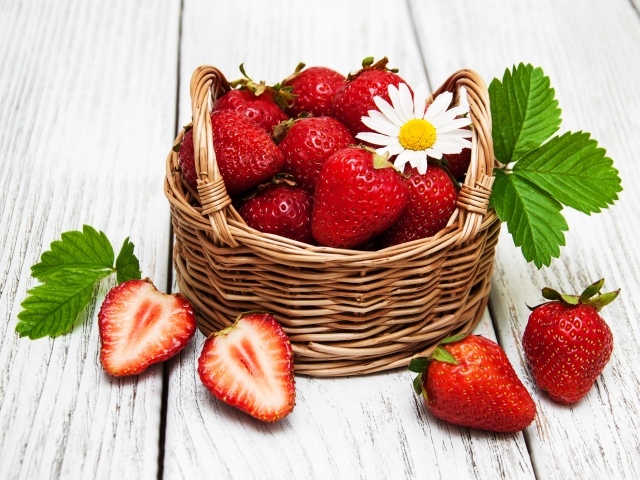 Плетеная корзинка с клубникой, ромашкой и зелеными листьями