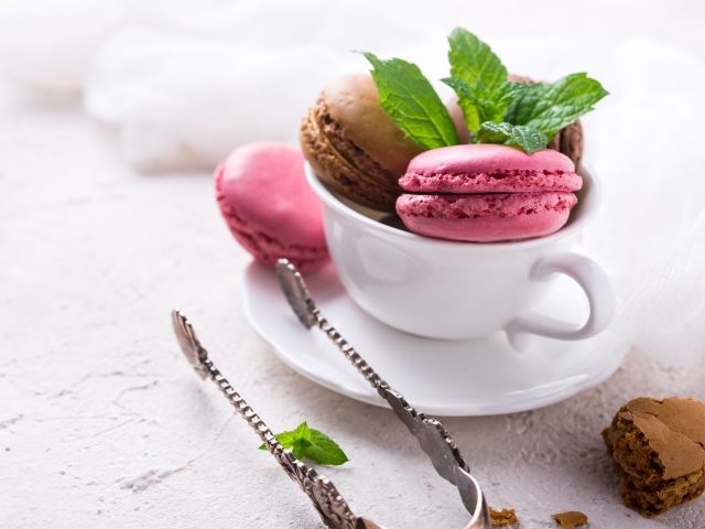 Разноцветный десерт макарун в белой чашке на столе