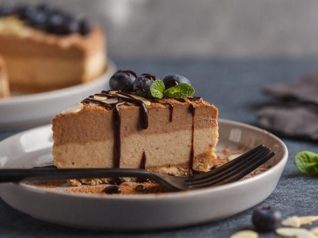 Кусок чизкейка с черникой и шоколадом на тарелке с вилкой