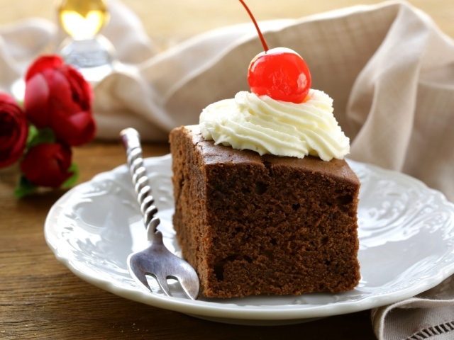 Кусок шоколадного пирога с кремом и вишней 