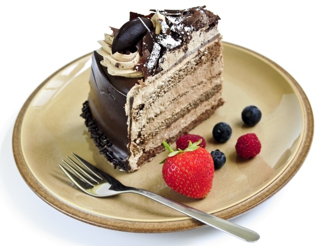 Кусок торта с кремом на тарелке с ягодами и вилкой