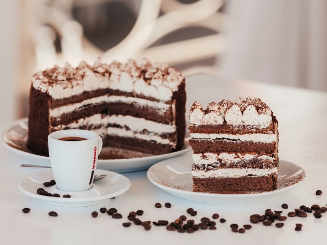 Аппетитный торт с чашкой кофе на столе