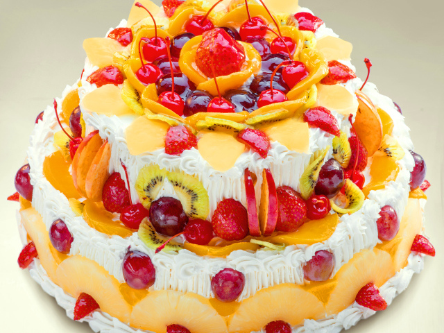 Красиво украшенный ягодами и фруктами торт с кремом