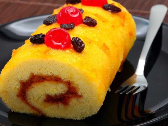 Бисквитный рулет с сухофруктами на тарелке с вилкой