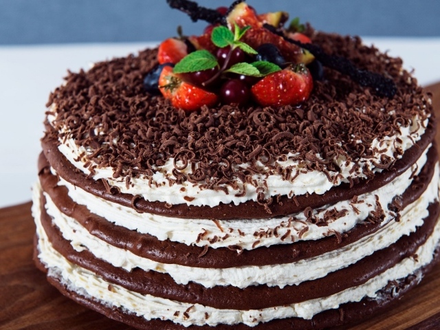 Шоколадный торт с кремом и тертым шоколадом украшен ягодами