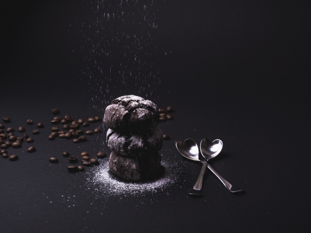 Шоколадное печенье с сахарной пудрой на черном фоне с кофейными зернами