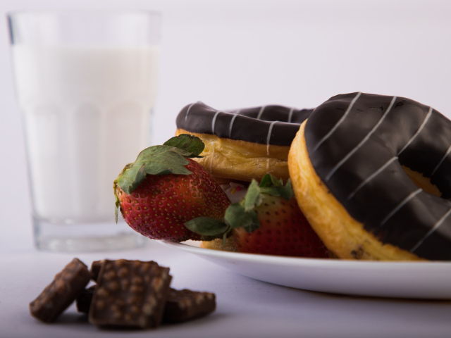 Пончики с шоколадной глазурью на тарелке с клубникой