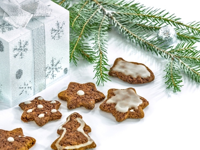 Новогоднее печенье с подарком и еловой веткой на белом фоне