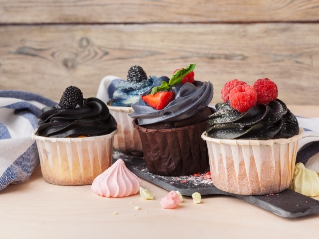 Вкусные кексы с ягодами и кремом  на столе 