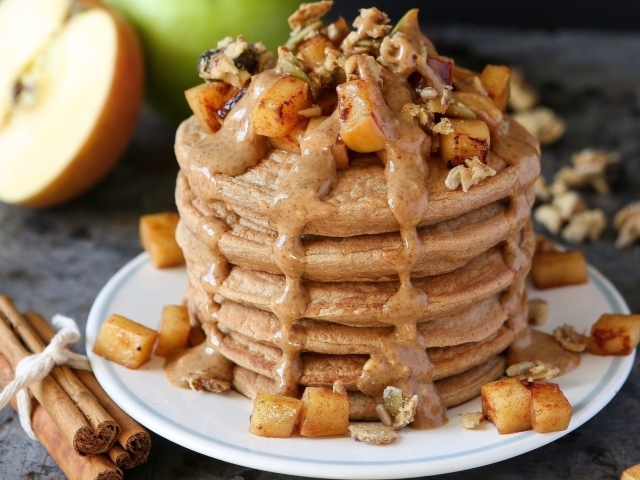 Вкусные оладьи с соусом и фруктами на столе с корицей