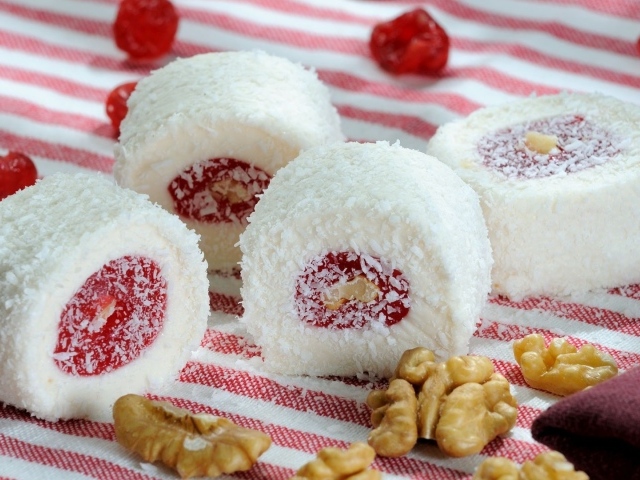 Десерт с джемом и кокосовой стружкой на столе с орехами