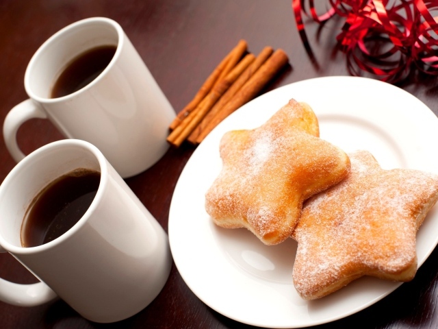 Пончики на столе с кофе и палочками корицы