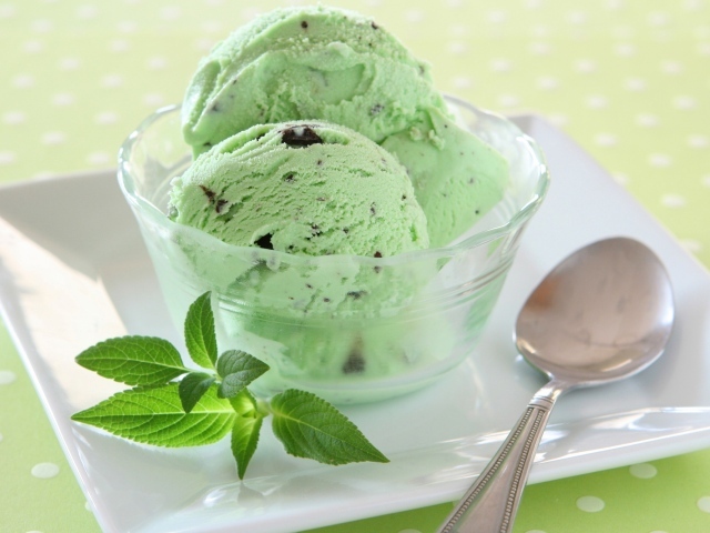 Зеленые шарики мороженого с шоколадом и мятой на тарелке с ложкой