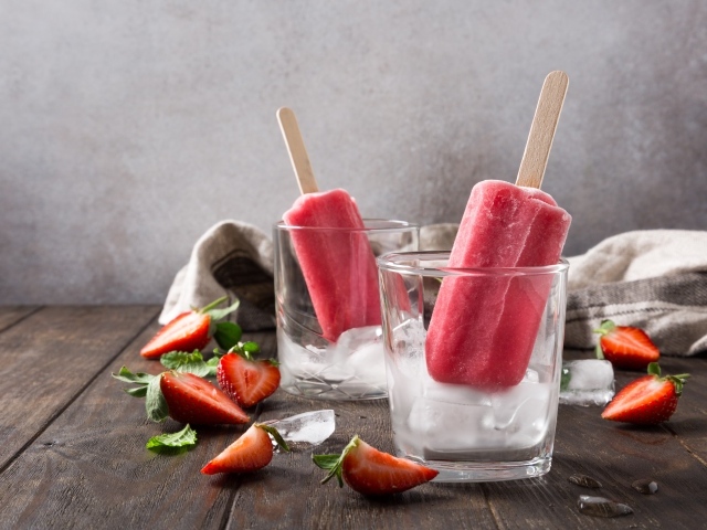 Фруктовое мороженое в стакане со льдом на столе с клубникой