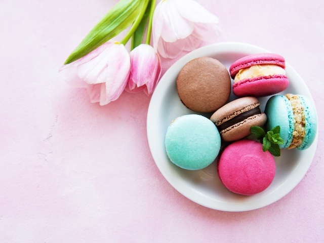 Десерт макарон на столе с розовыми тюльпанами