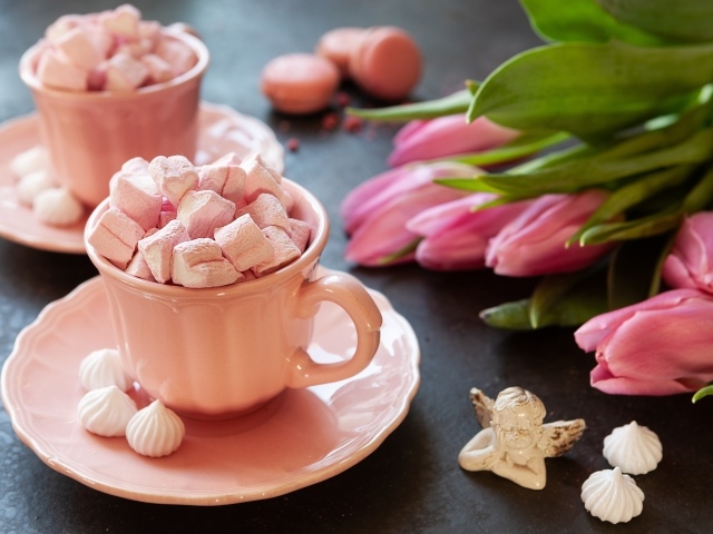 Маршмеллоу в розовой чашке на столе с букетом тюльпанов
