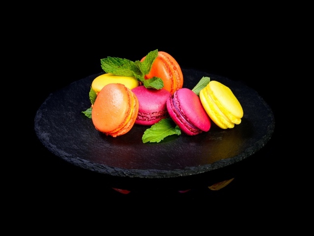 Разноцветный десерт макарон на черном фоне