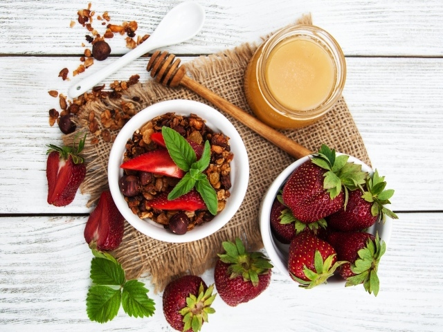 Орехи с ягодами клубники и медом на столе