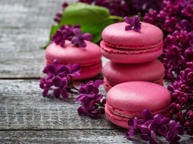 Розовый десерт макарон на столе с сиренью