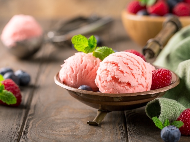 Шарики фруктового мороженого на столе с ягодами малины и черники 