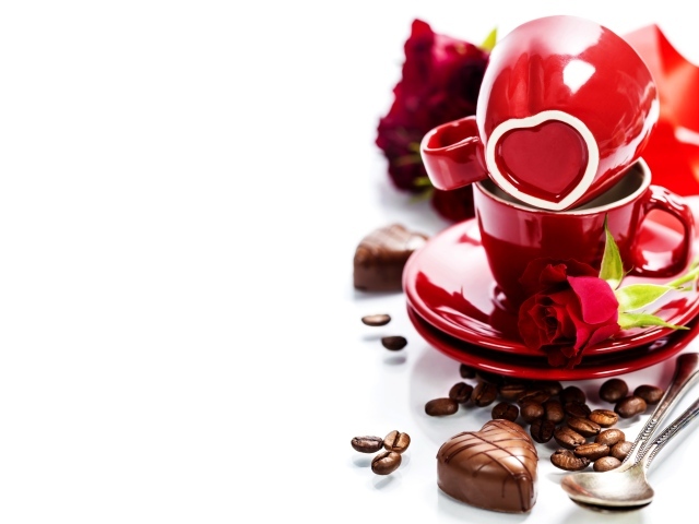 Красные чашки на белом фоне с шоколадными конфетами и кофейными зернами