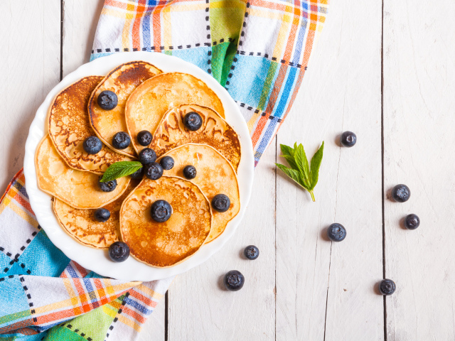 Румяные оладьи на тарелке с ягодами черники