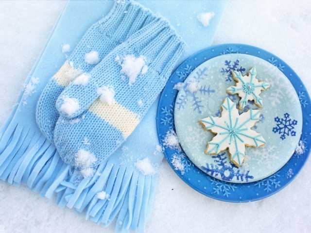 Печенье снежинки на снегу с шарфом и рукавицами