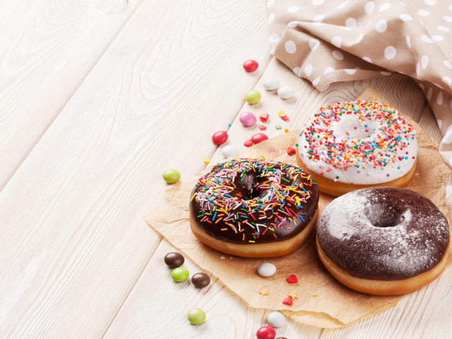 Три аппетитных пончика с глазурью на столе 