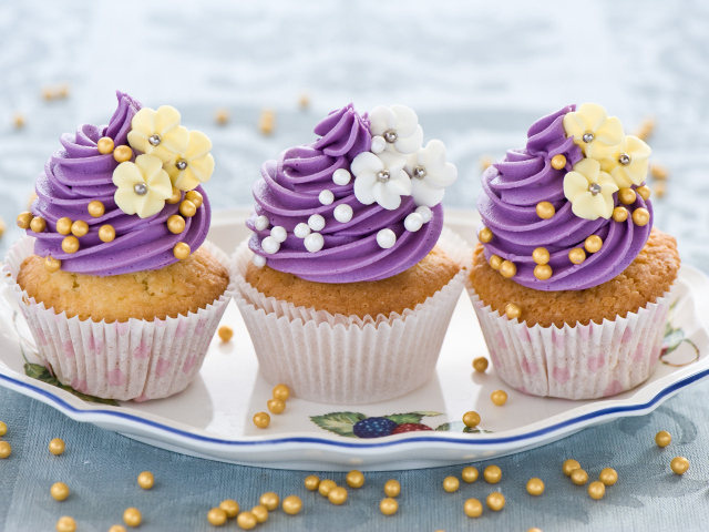Три вкусных кекса с фиолетовым кремом украшен цветами