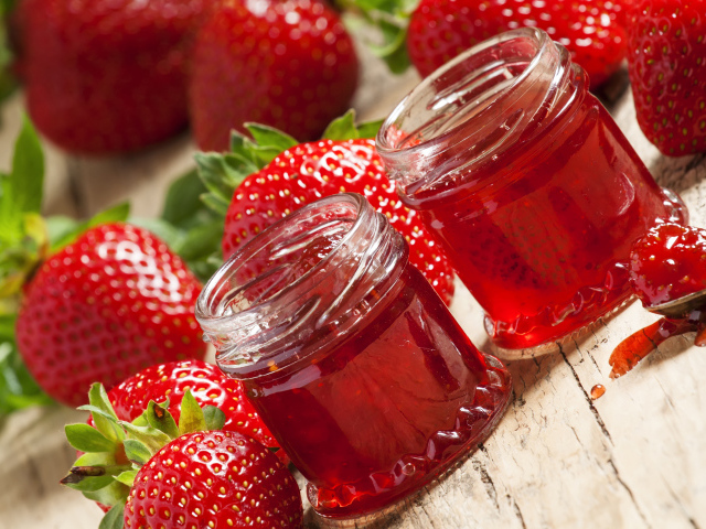 Две баночки клубничного джема на столе с клубникой