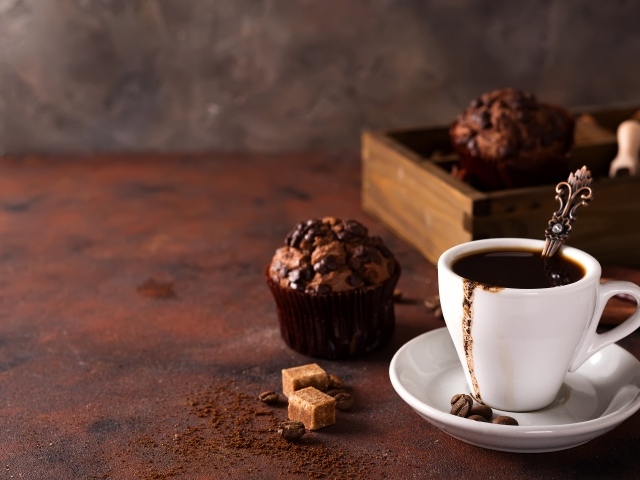 Белая чашка кофе и кекс с шоколадом на столе