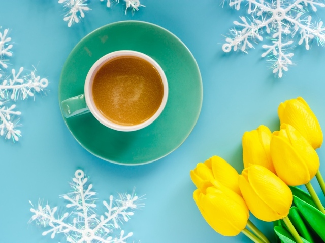 Чашка кофе на голубом фоне со снежинками и букетом желтых тюльпанов