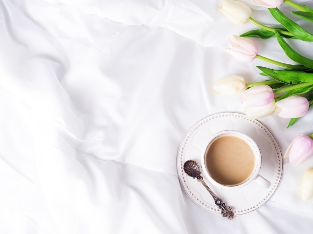 Чашка кофе на белом покрывале с тюльпанами