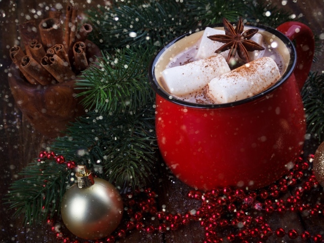 Чашка горячего какао с кусочками маршмеллоу и бадьяном на столе с еловой веткой 