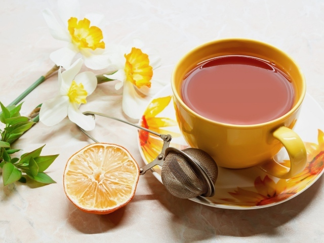 Чашка чаю на столе с лимоном и цветами нарцисса 
