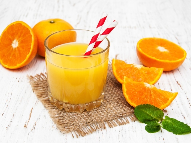Стакан свежего сока на столе с апельсинами
