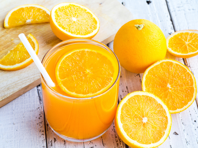 Стакан апельсинового сока на столе со свежими апельсинами на столе