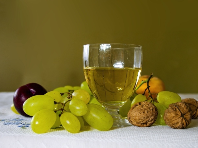 Бокал белого вина на столе с виноградом и орехами