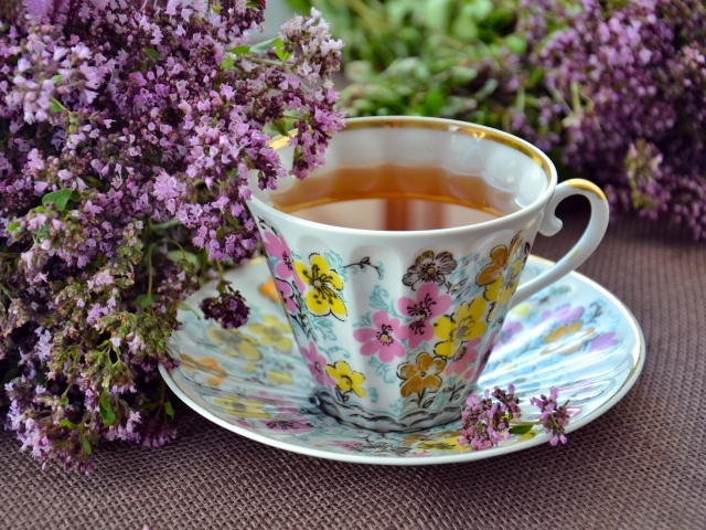 Красивая чашка чаю с цветами мяты на столе